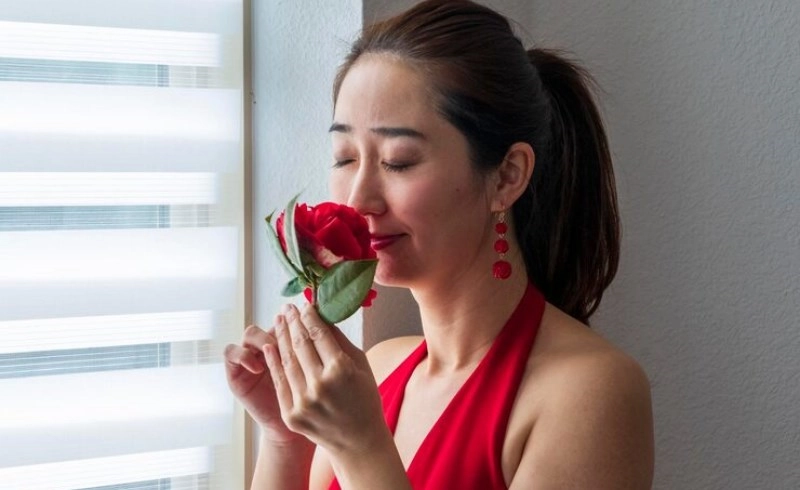 장미 꽃의 향기를 맡고 있는 빨간 드레스의 여자