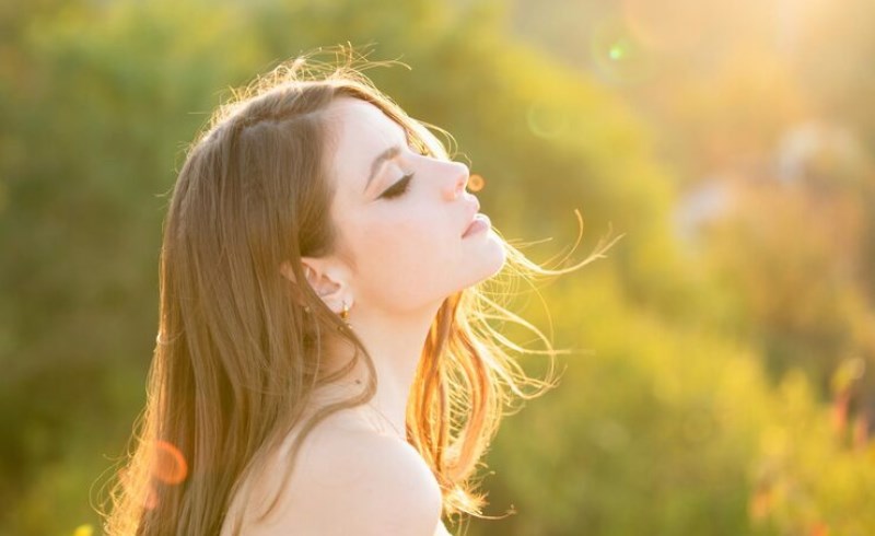 자연 속에서 편안하게 미소 짓는 여성의 모습