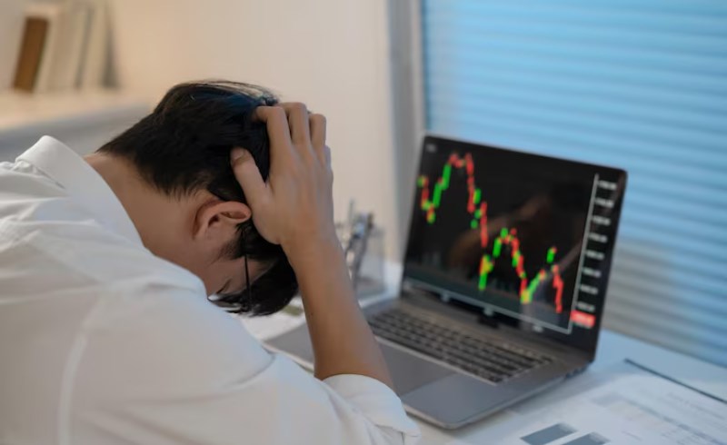 불안해 보이는 사람이 컴퓨터 앞에서 암호화폐 그래프를 바라보는 이미지