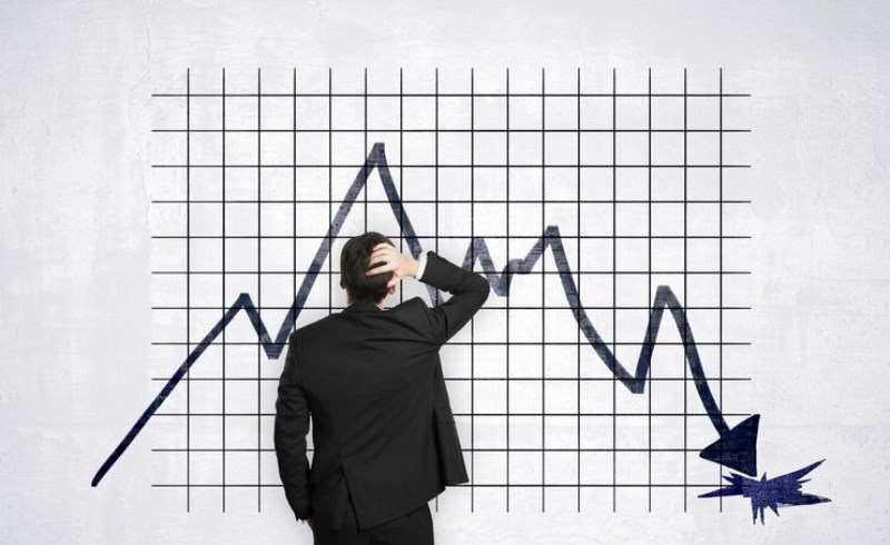 강한 바람에 흔들리는 나무와 그 아래 불안정한 주식 차트