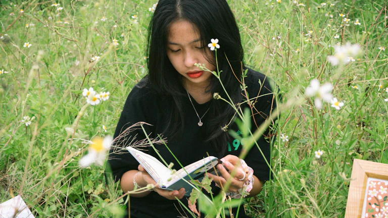 식물 옆에서 노트북으로 글을 쓰는 여성