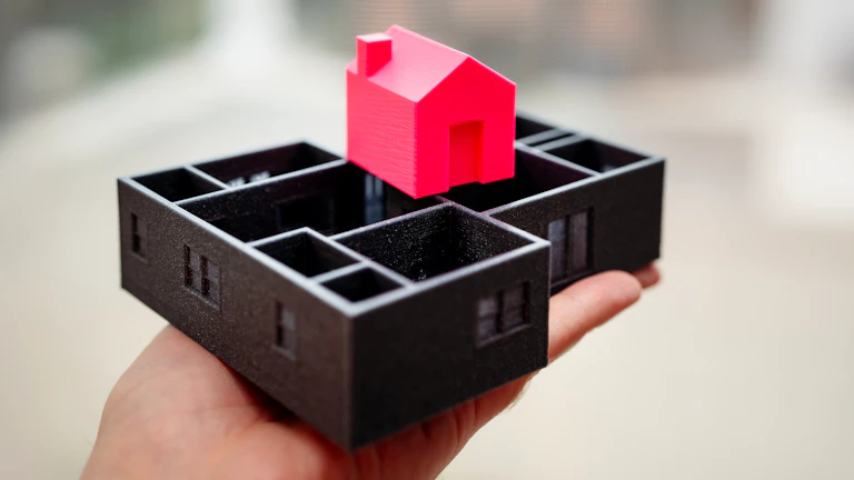 손으로 작은 집 모형을 들고 있는 모습